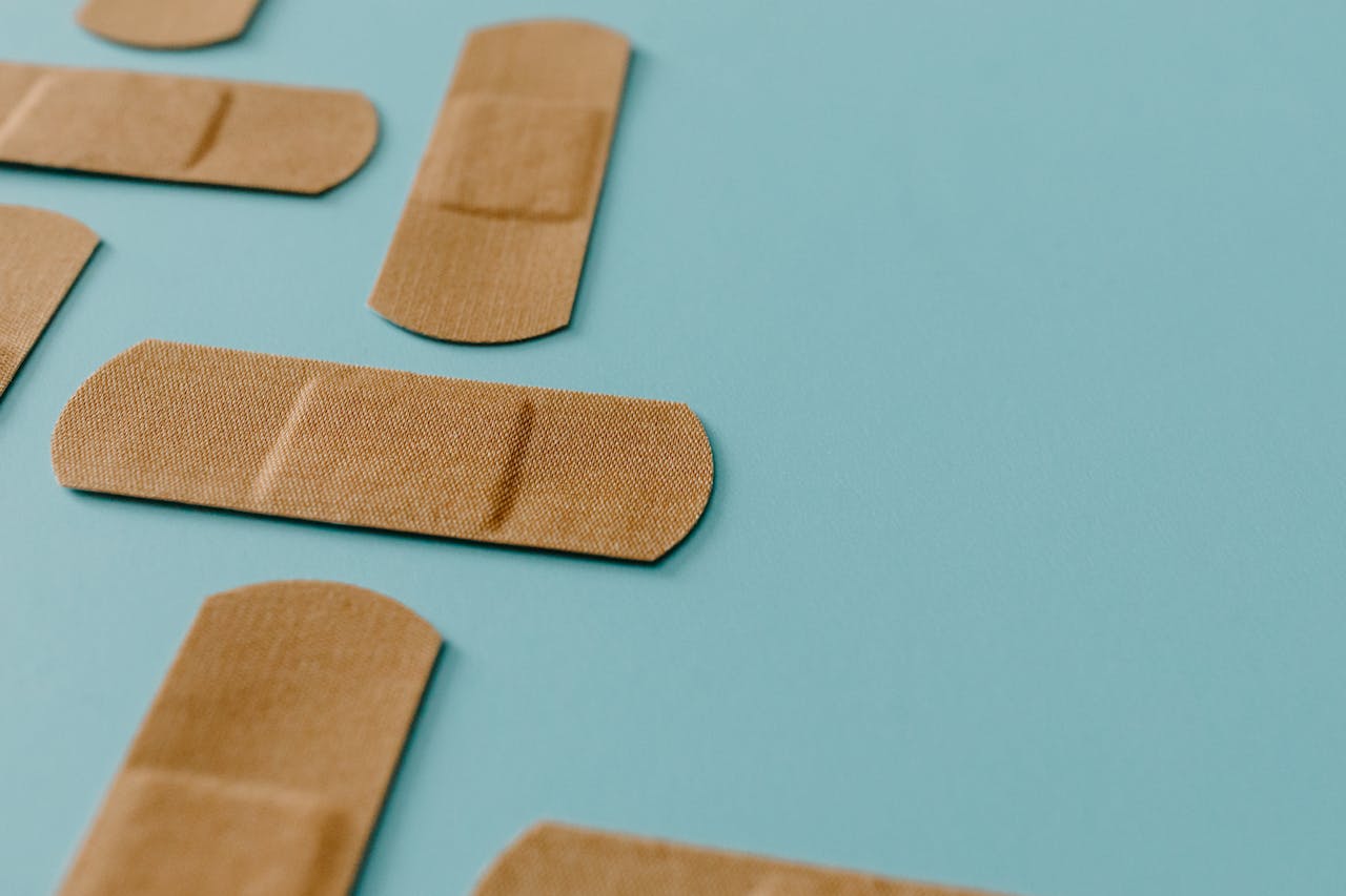 A close-up view of multiple band aids scattered on a pastel blue background, depicting first aid essentials.